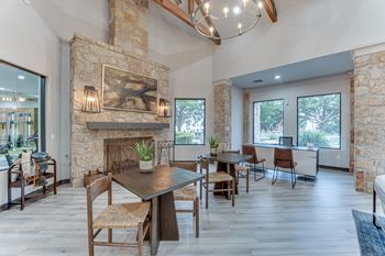 A modern dining room with a stone fireplace and wooden furniture at Limestone Ranch Apartments, Lewisville, TX